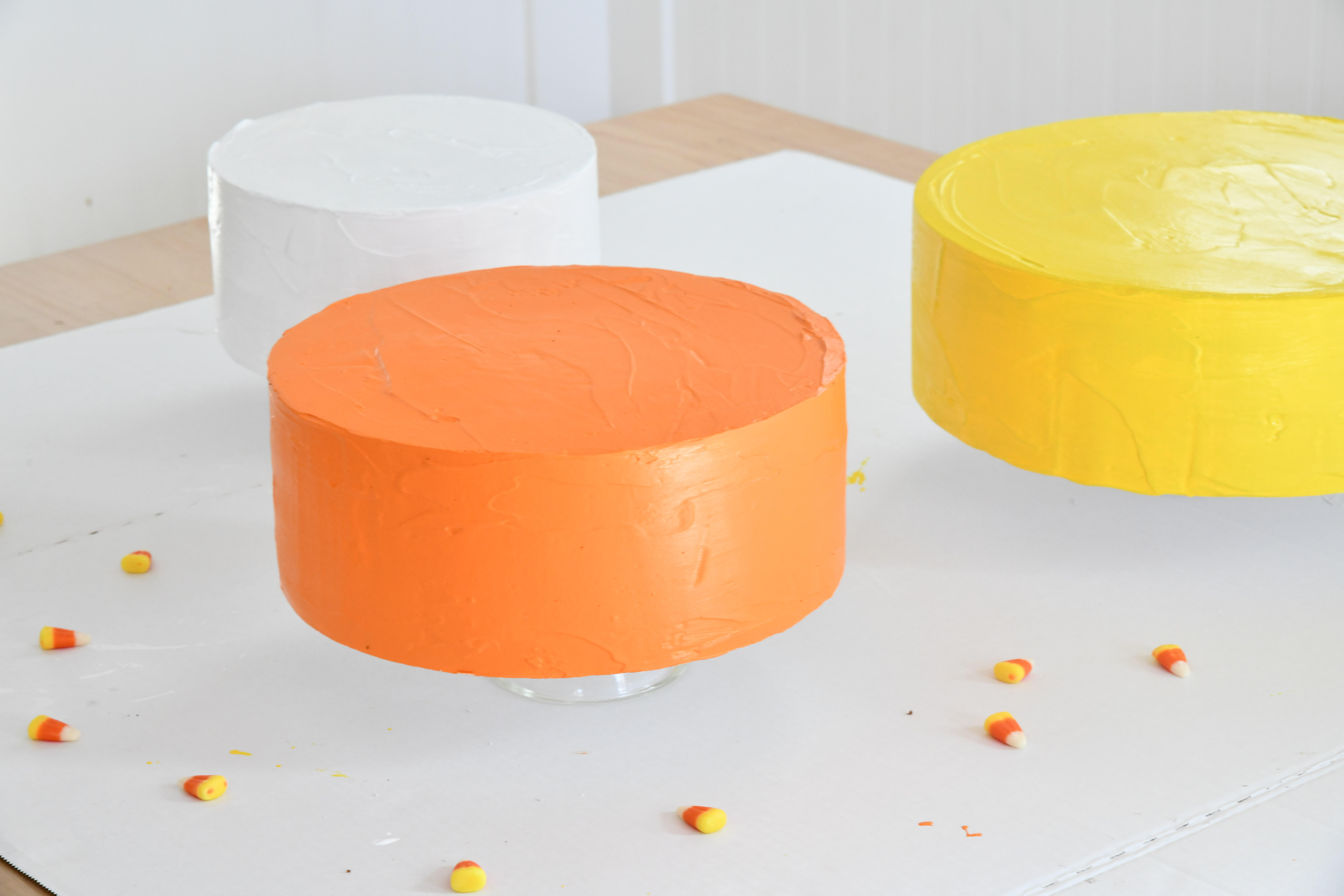 How To Make a Faux Cake: Three painted cakes on table one orange, one white, one yellow