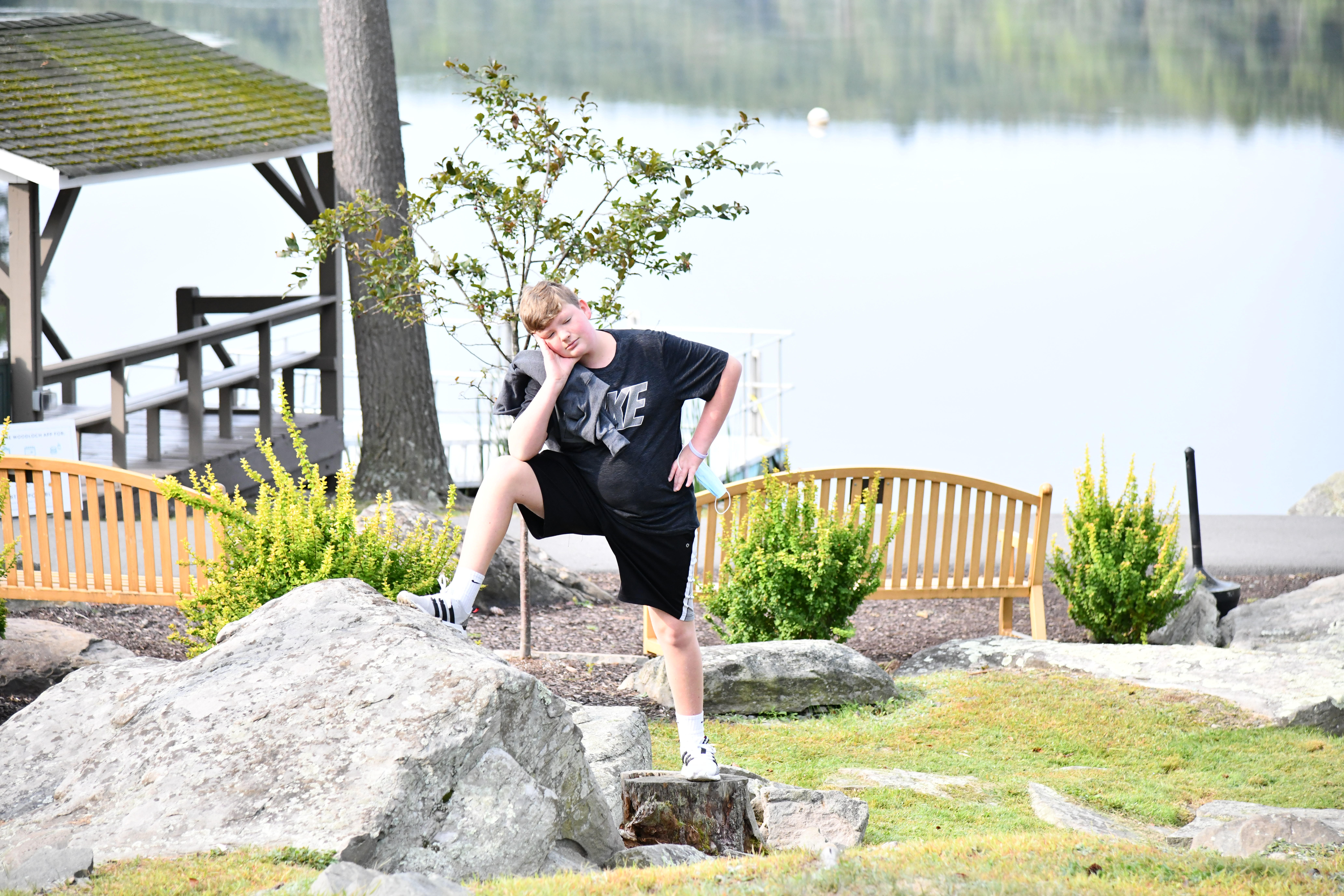 Kid standing by lake with foot on rock at Woodloch Resort Poconos