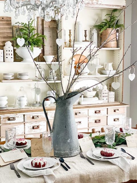 beautiful farmhouse vintage valentines day table setting with white dishes sink pitcher and greenery and branches