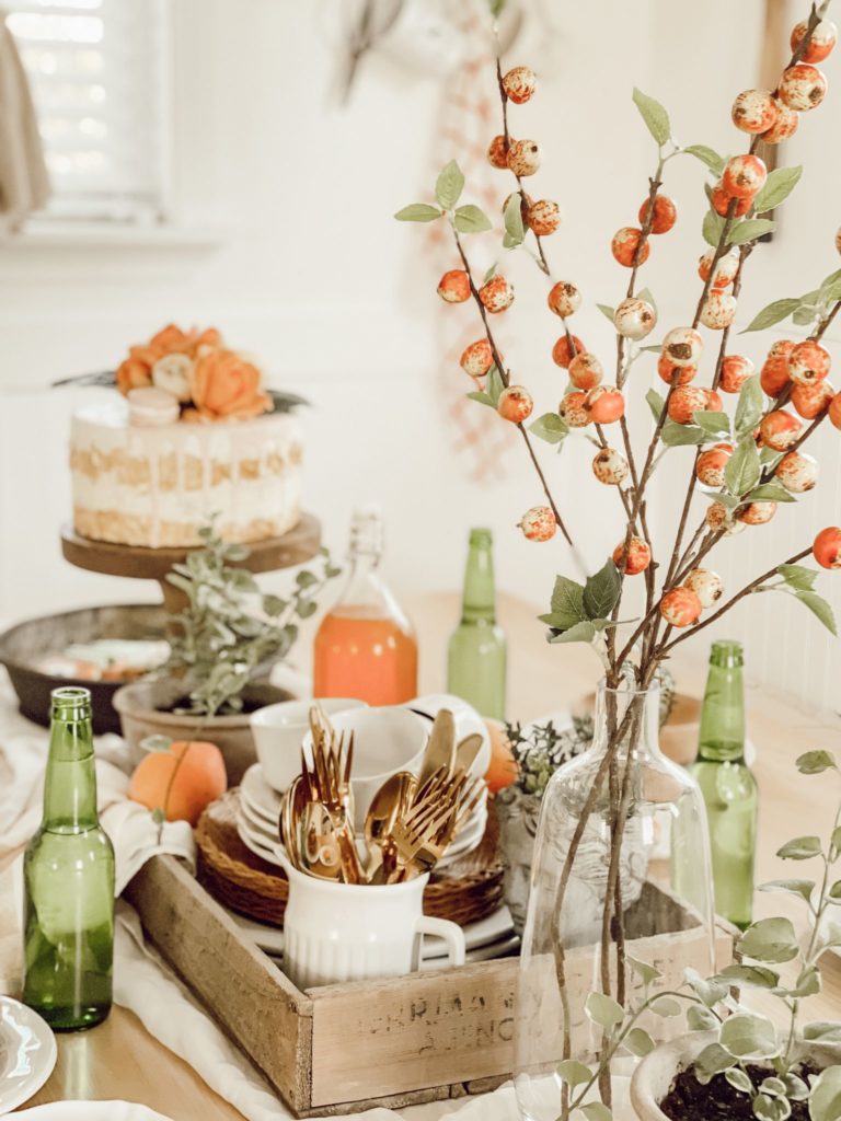 If You Love Peaches You Will Love this Tablescape view of table with peach florals glass bottles and faux cake in crate