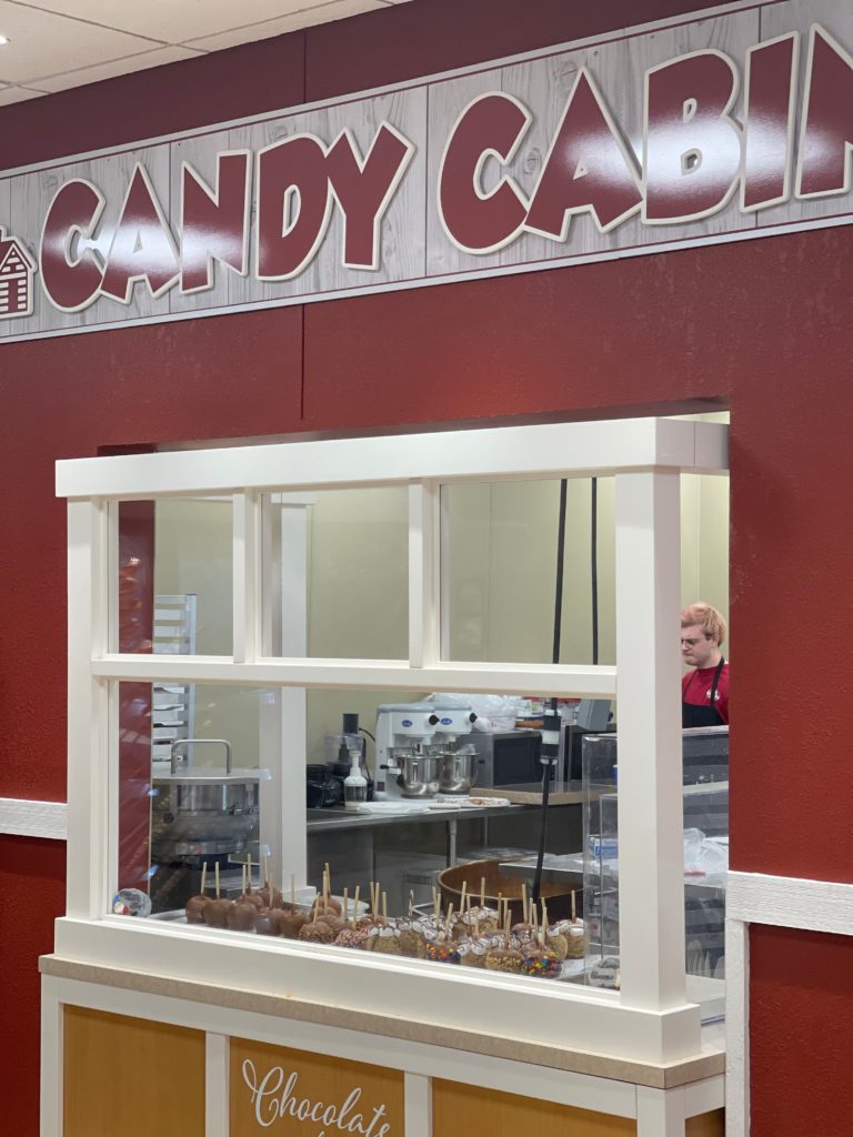 candy cabin sign with candy apples in food window and candy making kitchen behind the glass