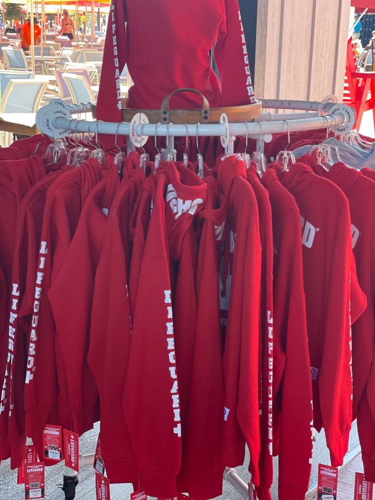 rack of red and white lifeguard sweatshirts with view of table and chairs in the background