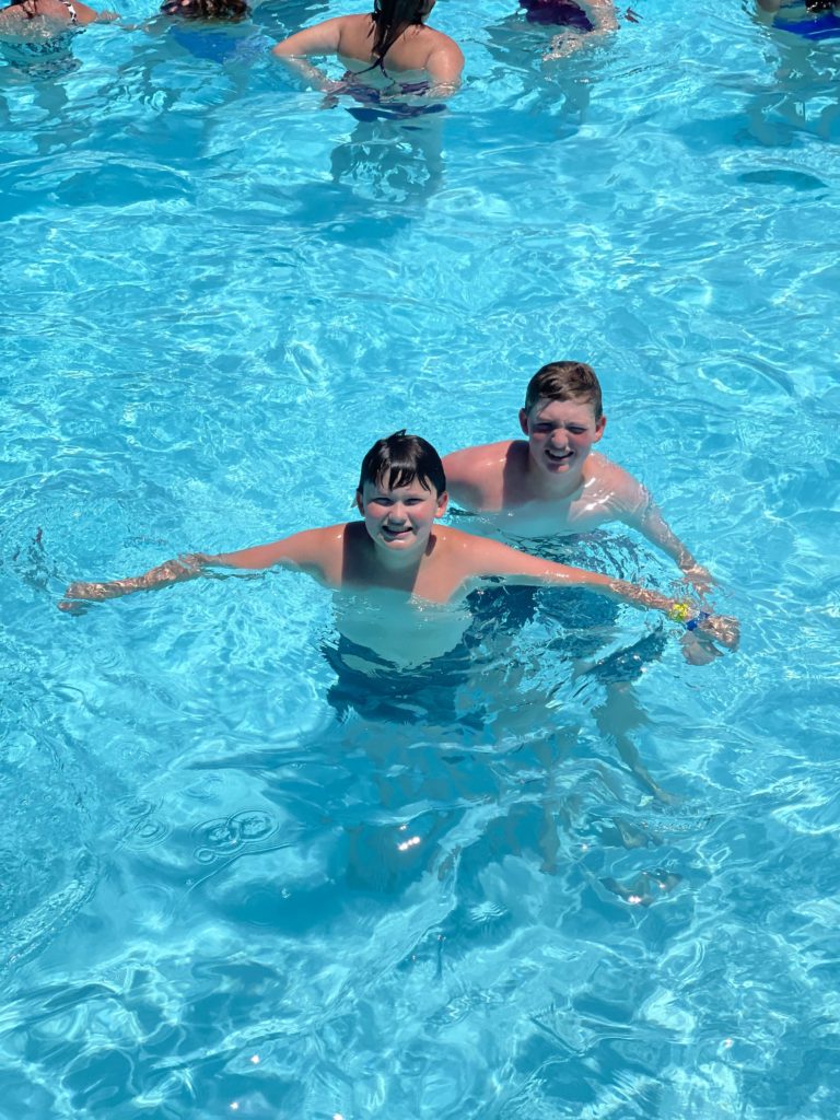 two teen boys in water smiling at camera in wave pool