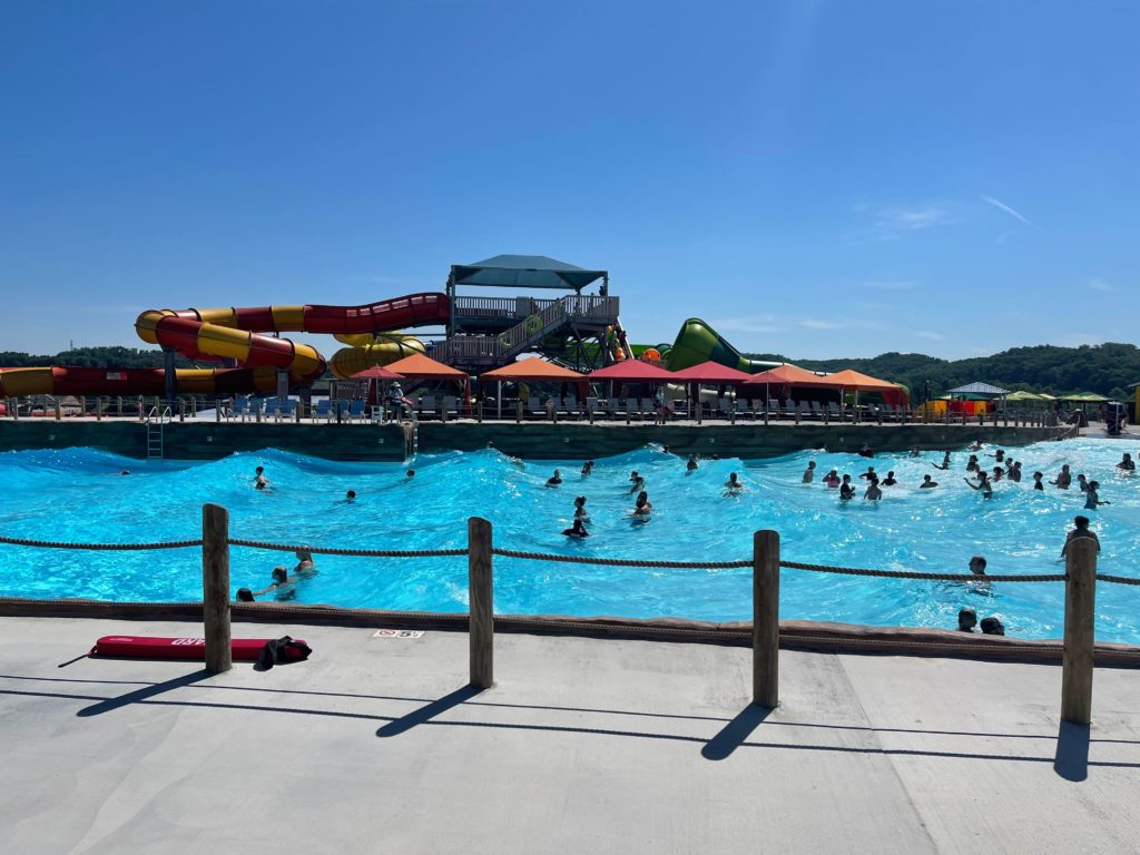 wood view of wave pool with people swimming and water slides in the background and cabanas