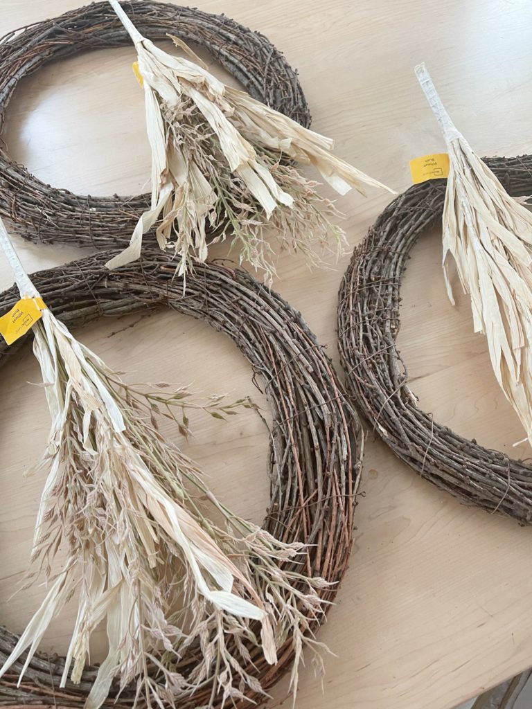3 Fall Grape Vine Wreaths with wheat bush on them sitting on table
