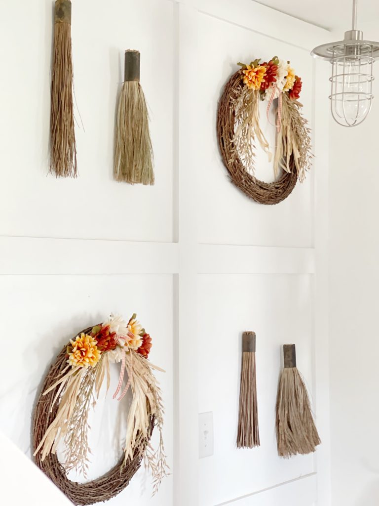 fall wrreaths with brooms on wall
