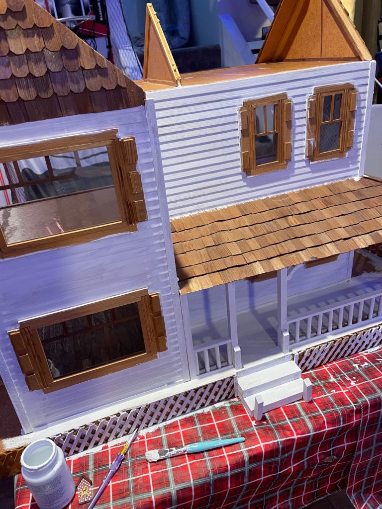 front of dollhouse with one coat white paint on it no roof