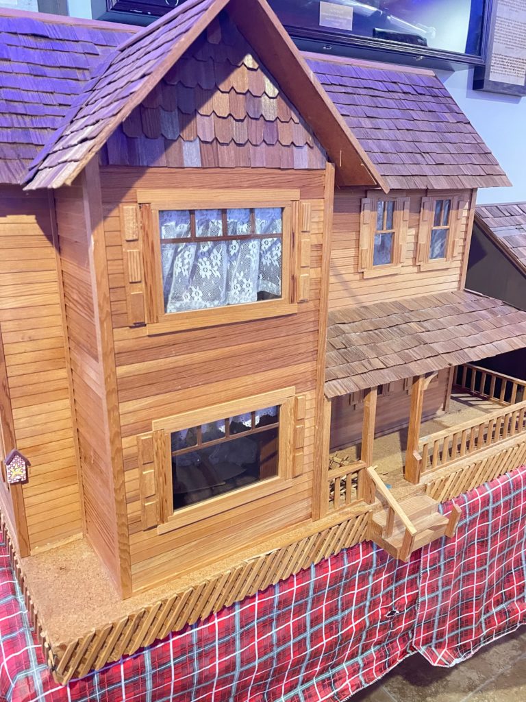 View of the front of wooden dollhouse with wrap around porch