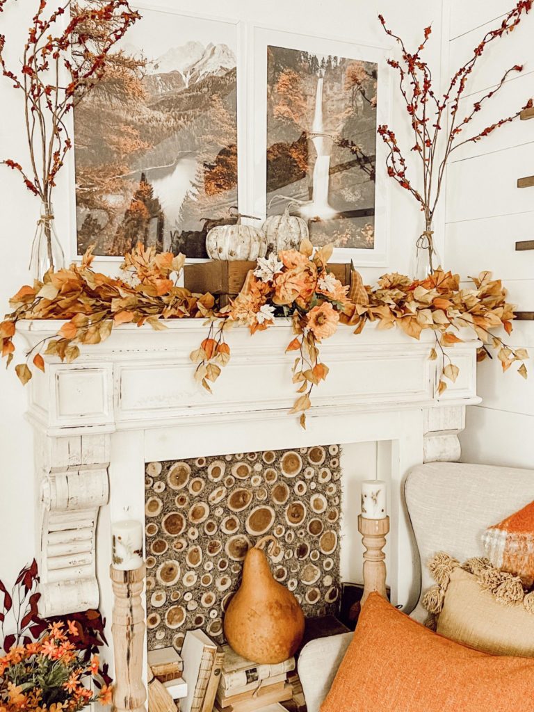 fall mantel decorated with leaves and two framed posters