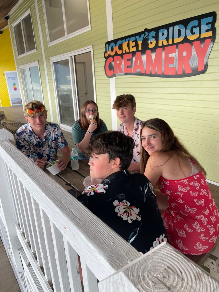 5 teens sitting outside ice cream shop around a table in the outer banks of NC