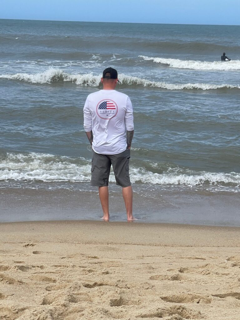 man standing on beach watching watching waves