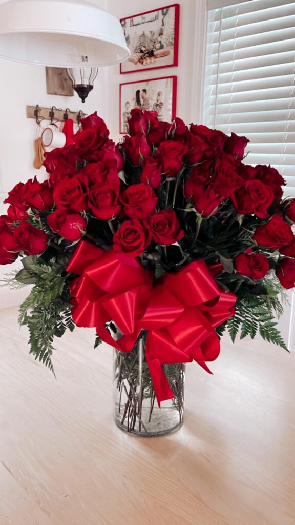 100 Long Stem Red Roses in vase on table